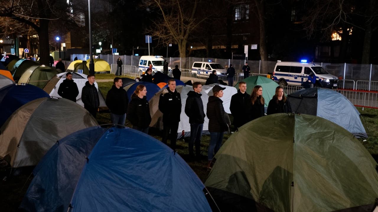 Tents and people in black in a park at night
