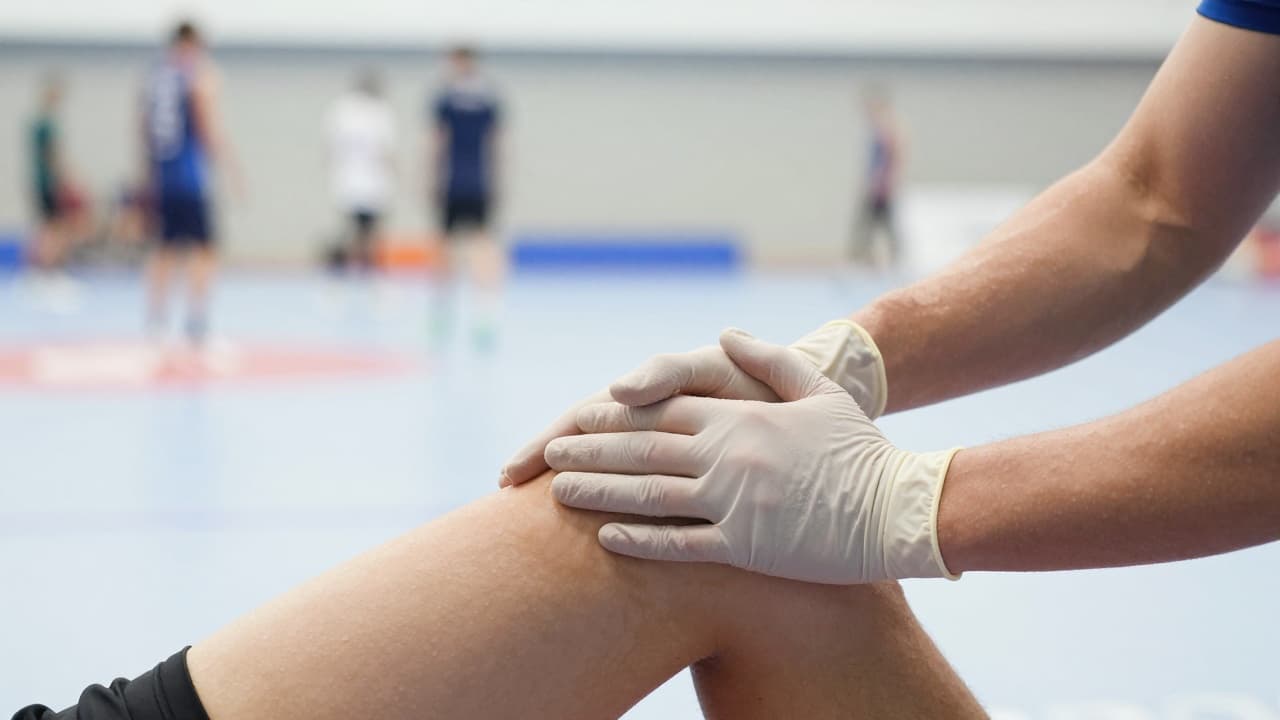 Hands in gloves massage a sportsman's leg